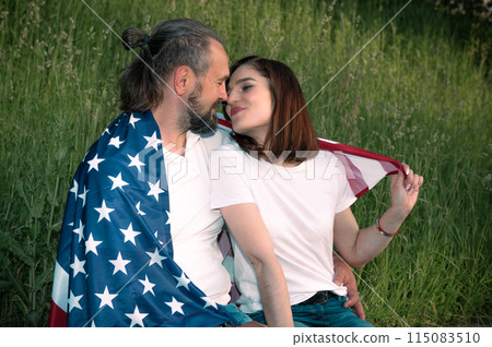 Loving couple celebrating USA Independence Day. Couple in love kissing and holding USA flag 115083510