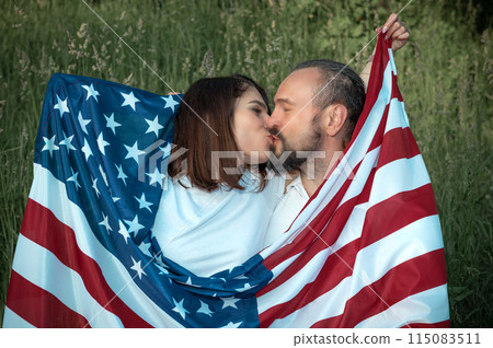 Loving couple celebrating USA Independence Day. Couple in love kissing and holding USA flag 115083511