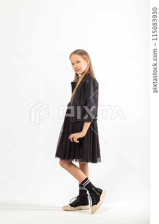 A full-length portrait of a young girl with long brown hair dressed in a hooligan style. A full-length portrait of a young girl with long brown hair dressed in a hooligan style. 115083930