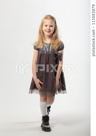 A little blonde girl in a dress and black boots poses 115083979