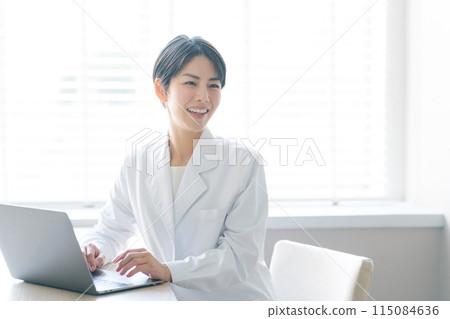 A woman in a white coat sitting by the window 115084636