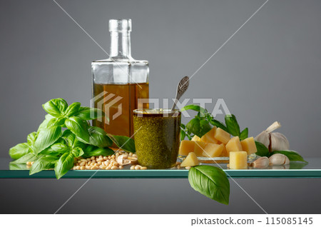 Pesto sauce and ingredients on a glass table. Pesto sauce and ingredients on a glass table. 115085145