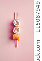 flat lay composition of three sushi rolls over chopsticks and pink background 115087949