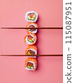 flat lay composition of three sushi rolls over chopsticks and pink background 115087951