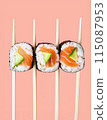 flat lay composition of three sushi rolls over chopsticks and pink background 115087953