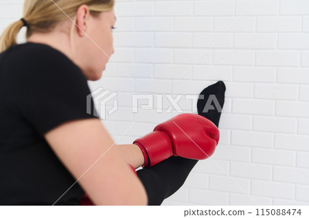 Female boxer stretching arms, warming up her body before intensive sport, wearing boxing gloves over white studio background. Sport. Cardo workout. People and active healthy lifestyle concept Female boxer stretching arms, warming up her body before intensive sport, wearing boxing gloves over white studio background. Sport. Cardo workout. People and active healthy lifestyle concept 115088474
