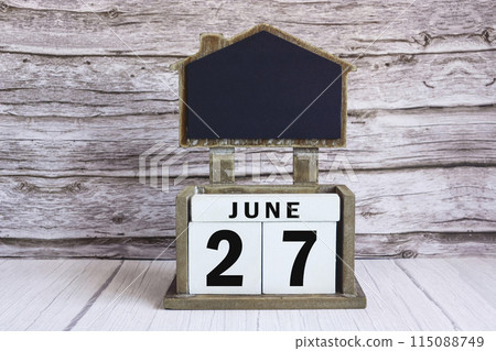 Chalkboard with June 27 date on white cube block on wooden table. Chalkboard with June 27 date on white cube block on wooden table. 115088749