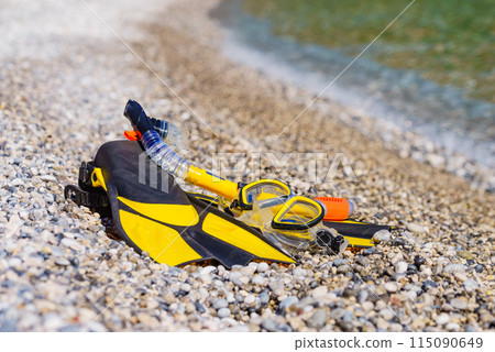 Flippers and snorkeling tube on sea shore 115090649