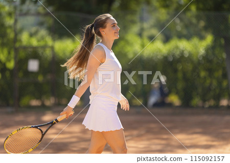 A woman in a white tank top and white skirt is holding a tennis racket A woman in a white tank top and white skirt is holding a tennis racket 115092157