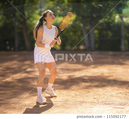 A woman is playing tennis on a clay court 115092177