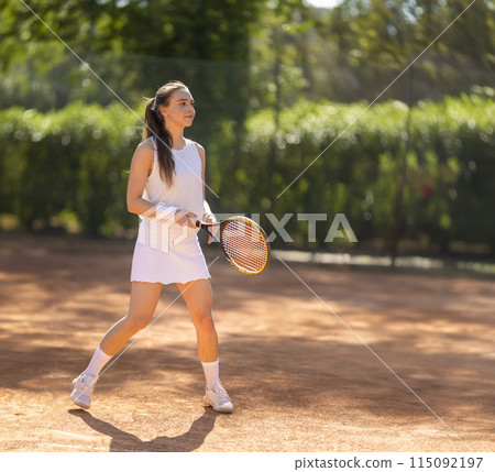 A woman is playing tennis on a clay court 115092197