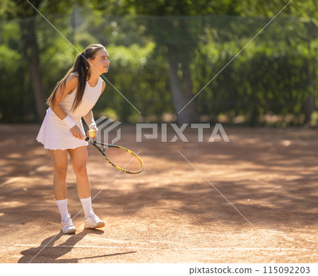 A woman is playing tennis on a clay court 115092203