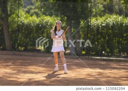 A young woman is playing tennis on a clay court 115092204