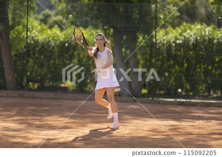 A woman is playing tennis on a clay court 115092205