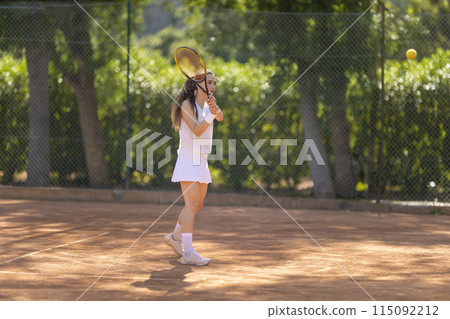 A woman is playing tennis on a clay court 115092212