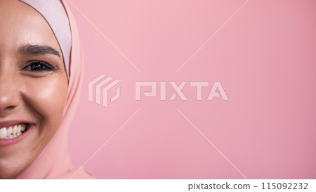Joyful smile. Happy emotion. Half face portrait of amused satisfied pleased cheerful woman in hijab isolated on pink empty space background. 115092232