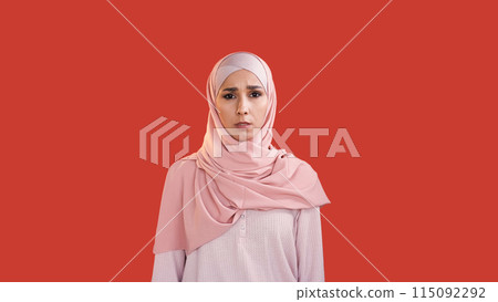 Scared woman. Fear anxiety. Stress problem. Disturbed shocked frightened female face in hijab with open mouth isolated on red copy space background. 115092292