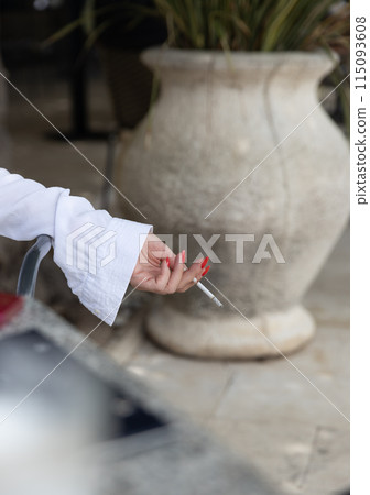 Woman Holding a Cigarette with Red Nails 115093608