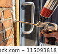 Window installation. The process of insulating windows with construction foam. A builder's hand seals the cracks between the building and the window frame. Construction and insulation of the building. 115093818
