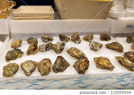 Fresh Oysters on the counter on ice in store. Oysters for sale at the seafood market. Aphrodisiac sea restaurant, expensive fresh food, dish menu Fresh Oysters on the counter on ice in store. Oysters for sale at the seafood market. Aphrodisiac sea restaurant, expensive fresh food, dish menu 115095634