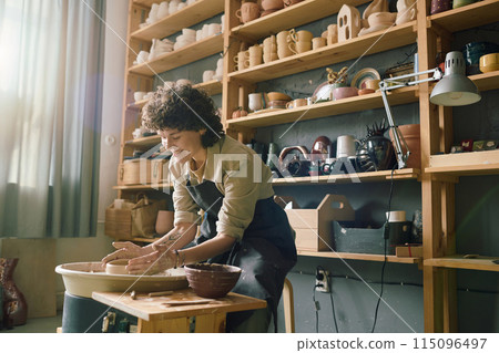 Creative Caucasian woman enjoying making bowl on potters wheel in modern workshop, copy space Creative Caucasian woman enjoying making bowl on potters wheel in modern workshop, copy space 115096497