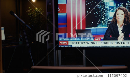 TV left open at night on streaming service channel with news reporter covering different subjects. Close up shot of smart TV in empty dimly lit apartment showing journalist talk about reportages 115097402