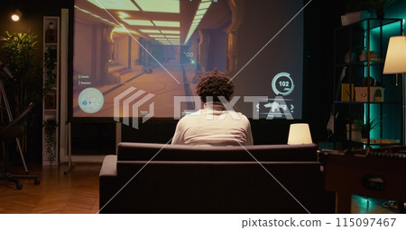 African american man plays first person shooter videogame on ultrawide smart TV with gun shooting at enemies. BIPOC gamer enjoying PvP online multiplayer game with players competing against each other 115097467