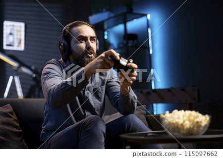 Man showing surprise facial expression while playing videogames on gaming console with teammates. Player acting shocked after being defeated by foes in game, discussing with friends through headset Man showing surprise facial expression while playing videogames on gaming console with teammates. Player acting shocked after being defeated by foes in game, discussing with friends through headset 115097662