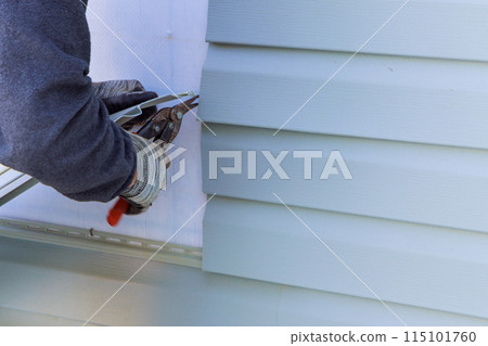 During exterior house renovations, damaged plastic siding is replaced 115101760