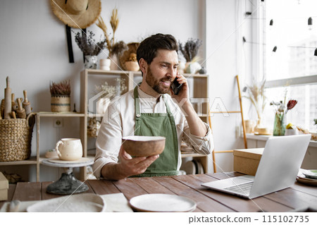 Young bearded man potter taking order for purchase of tableware. 115102735