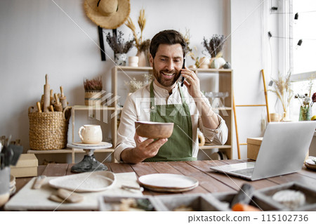 Young bearded man potter taking order for purchase of tableware. 115102736
