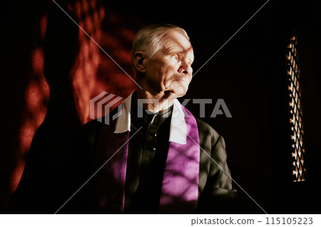 Medium closeup of senior Caucasian Catholic priest hearing out penitent in confessional booth, copy space Medium closeup of senior Caucasian Catholic priest hearing out penitent in confessional booth, copy space 115105223
