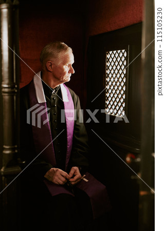 Vertical medium long shot of Catholic priest waiting for penitent in confessional, copy space 115105230
