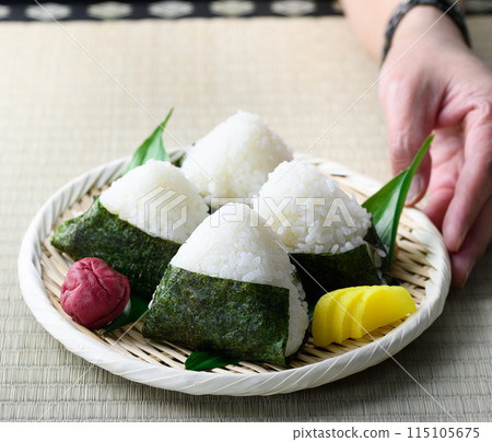Rice balls wrapped in roasted seaweed and traditional sour pickled plums eaten on tatami mats 115105675