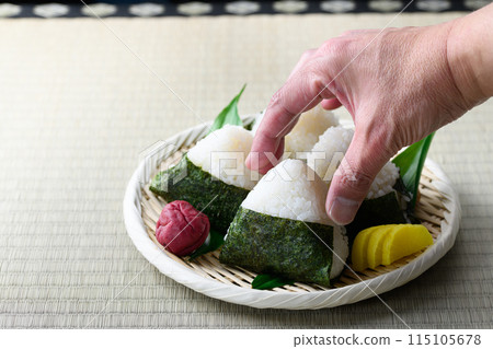 烤海藻包著的飯糰和傳統酸梅子在榻榻米上吃 烤海藻包著的飯糰和傳統酸梅子在榻榻米上吃 115105678