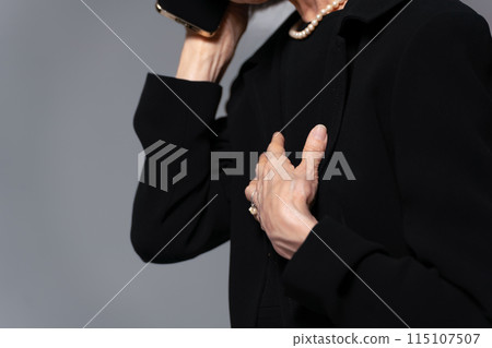 Senior woman in mourning clothes talking on smartphone 115107507