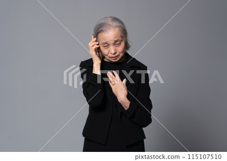 Senior woman in mourning clothes talking on smartphone 115107510