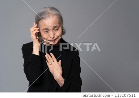Senior woman in mourning clothes talking on smartphone 115107511
