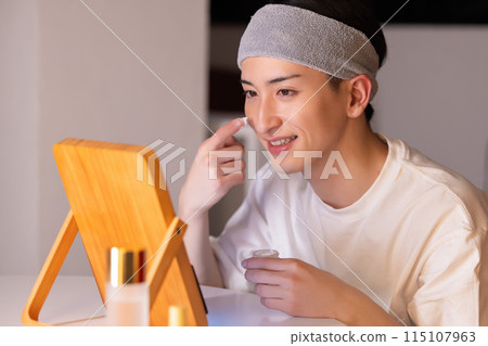 Living room at night: A young man doing skin care 115107963