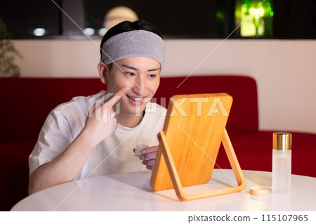 Living room at night: A young man doing skin care 115107965