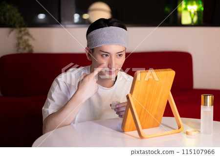 Living room at night: A young man doing skin care 115107966