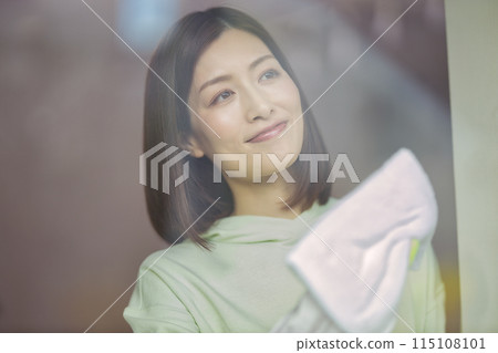 A middle-aged woman wiping windows in the living room 115108101