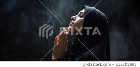 A Muslim woman prays at night, her side profile illuminated by soft light. The background is dark, creating a peaceful night mood with ample copy space. Generative AI. 115108695