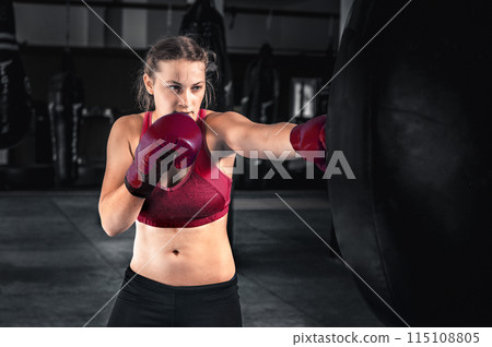 Attractive young woman boxing at the gym. Female boxer preparing for training in boxing club 115108805