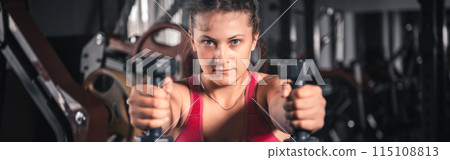 Young woman with dumbbells in the gym. Portrait of young attractive woman in sport clothes holding weight dumbbell doing fitness workout Young woman with dumbbells in the gym. Portrait of young attractive woman in sport clothes holding weight dumbbell doing fitness workout 115108813