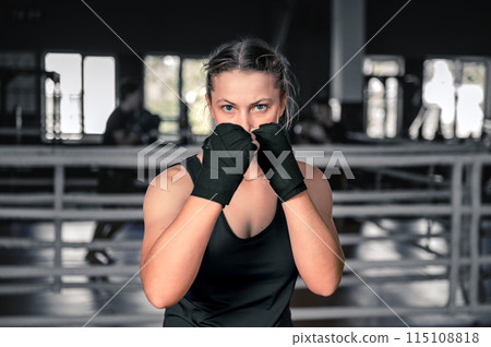 Young woman getting ready for exercise in the gym. Woman boxer getting ready near the ring Young woman getting ready for exercise in the gym. Woman boxer getting ready near the ring 115108818