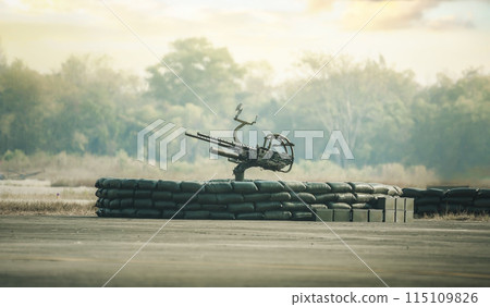 An anti-aircraft cannon and Military  fighting scene. Piece of an anti-aircraft artillery batteries against, World War Soldiers Below Cloudy Skyline at sunset. Attack scene. 115109826