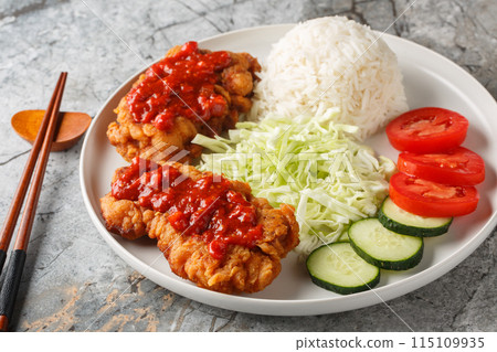 Ayam geprek is a typical Indonesian dish of fried chicken with sambal served with white rice, cucumber, tomato and cabbage closeup on the plate. Horizontal Ayam geprek is a typical Indonesian dish of fried chicken with sambal served with white rice, cucumber, tomato and cabbage closeup on the plate. Horizontal 115109935