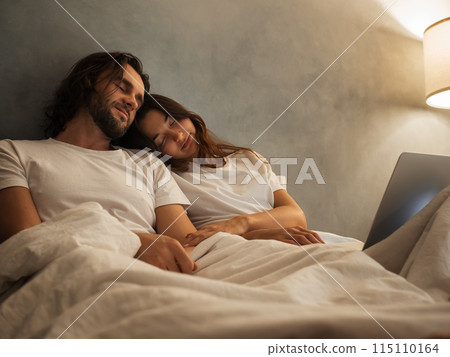 Couple Sleeping in Bed with Laptop Nearby Couple Sleeping in Bed with Laptop Nearby 115110164
