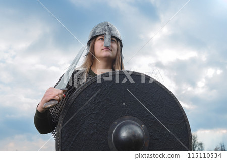 Woman soldier of the medieval army. Portrait of woman in image of medieval warrior. Beautiful woman in medieval chain mail. Woman soldier of the medieval army. Portrait of woman in image of medieval warrior. Beautiful woman in medieval chain mail. 115110534
